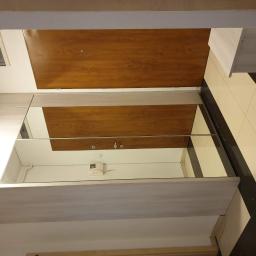 Forma drewna - Wnętrze przedpokoju z zabudową szafy z lustrzanymi drzwiami przesuwnymi i drewnianą okleiną, widoczny fragment podłogi w czarno-białe pasy.