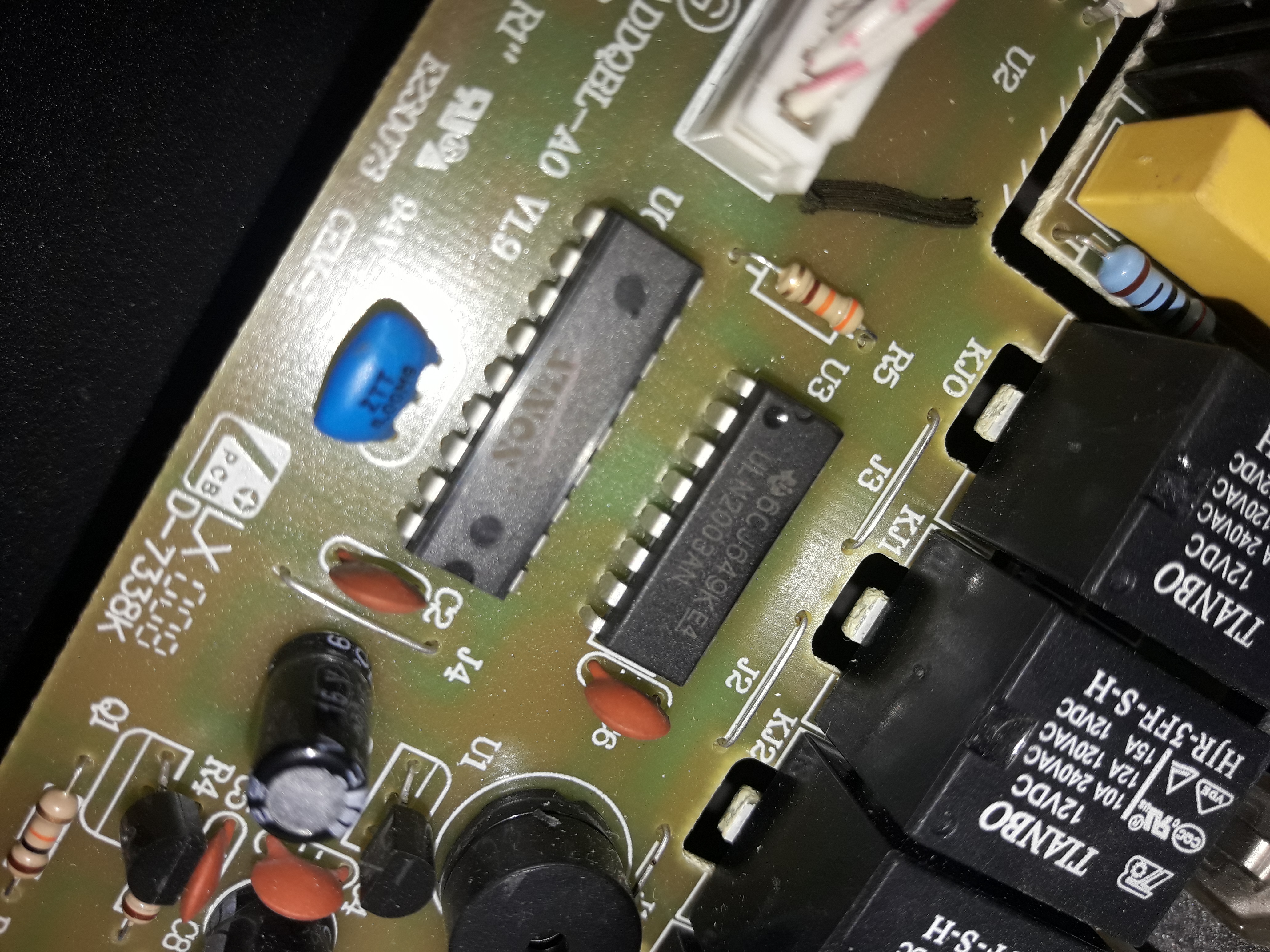 Zbliżenie na płytę drukowaną z elementami elektronicznymi, w tym układy scalone, rezystory i przekaźniki TIANBO, widoczne oznaczenia na laminacie.