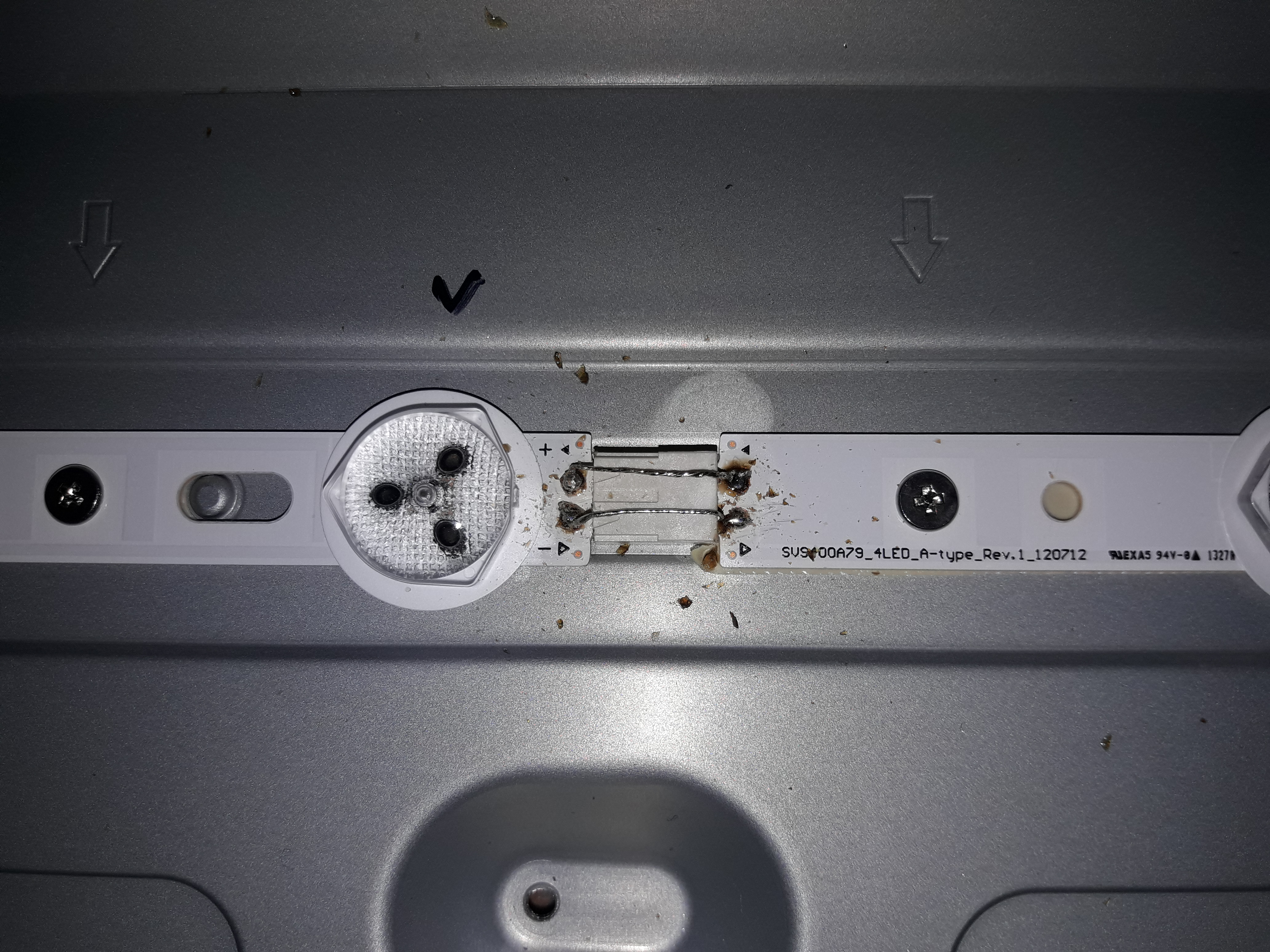 Wnętrze obudowy telewizora z widoczną listwą LED po naprawie, ślady lutowania i zabrudzenia wokół diody.