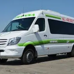 Biały bus Mercedes Sprinter z zielonymi akcentami i logo firmy TRANS-A na tle błękitnego nieba i betonowej nawierzchni.