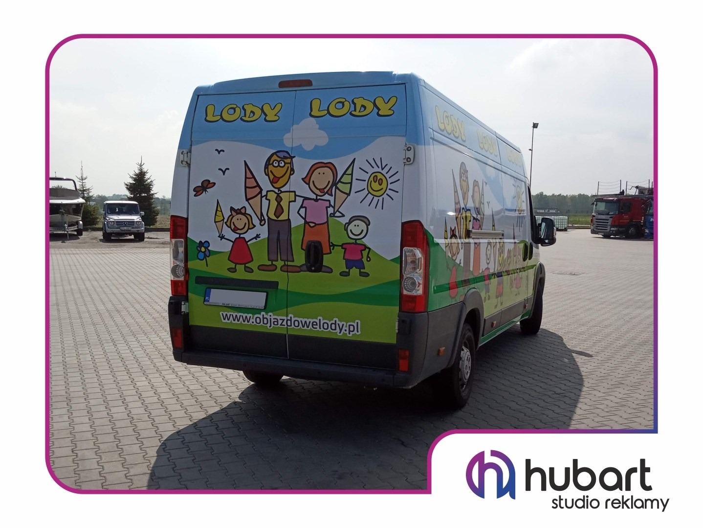 Samochód dostawczy z kolorową grafiką przedstawiającą rodzinę i lody, zaparkowany na placu z kostki brukowej, widoczny tył i bok pojazdu z adresem strony internetowej.
