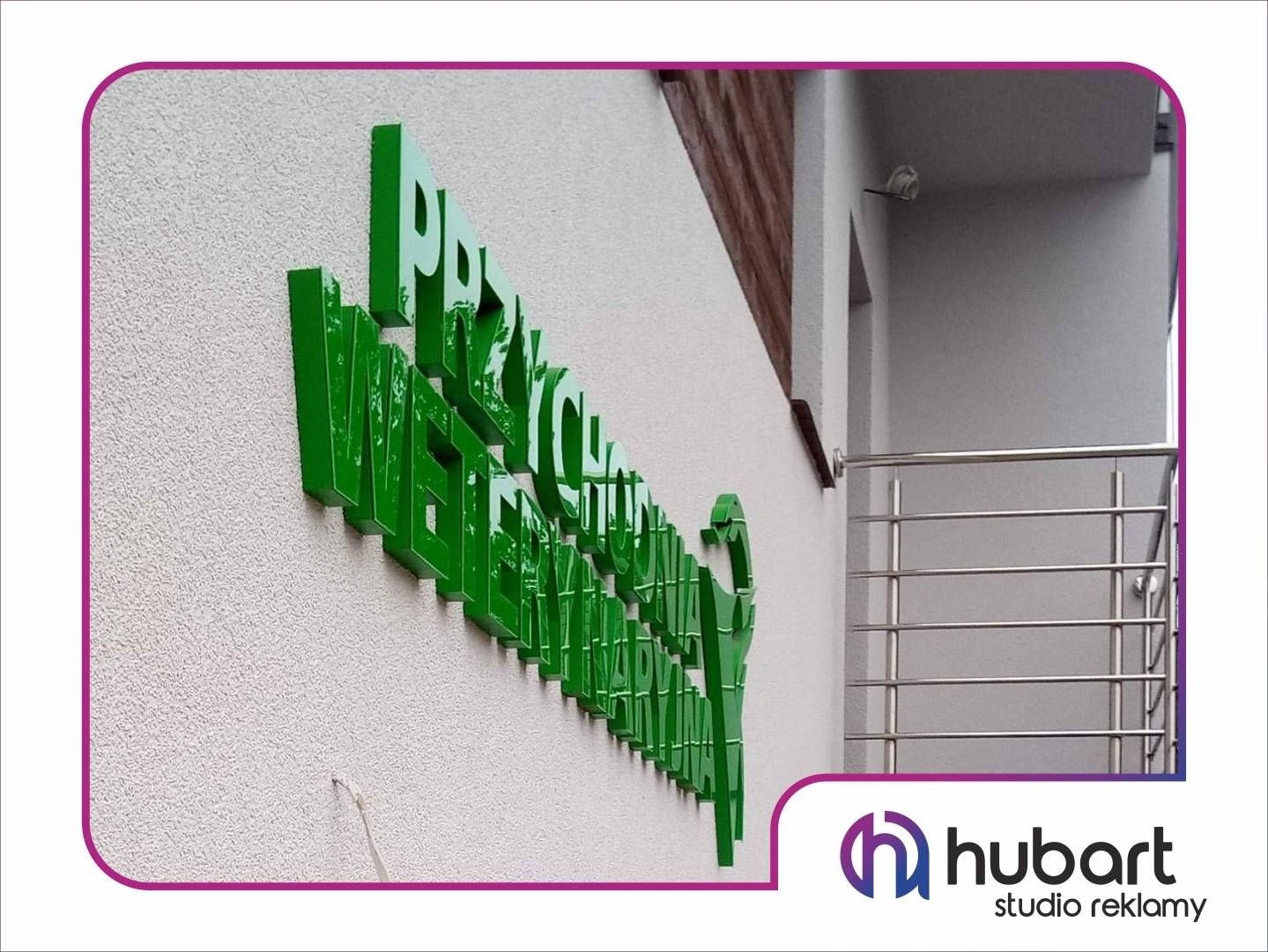 Zielony, przestrzenny napis na elewacji budynku z widocznymi detalami faktury tynku i elementami architektonicznymi w tle.