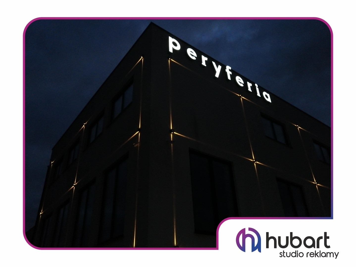 Budynek z podświetlanym napisem 'Peryferia' na fasadzie, oświetlony dodatkowymi pionowymi liniami świetlnymi, widok z dołu w nocy.