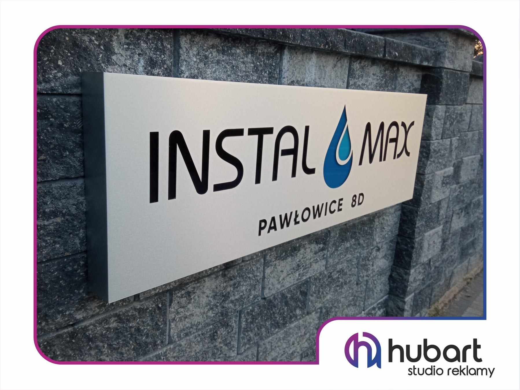 Szyld reklamowy firmy Instal Max z adresem Pawłowice 8D, zamocowany na szarej ścianie z kamienia łupanego.