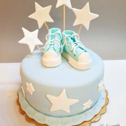 Cukiernia Chmielewski - Tort w Lublinie z dekoracjami: niebieski tort z białymi gwiazdami i parą turkusowych butów z lukru na wierzchu, dodatkowo pięć białych gwiazd na patykach.