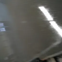 Świeżo wylana, mokra posadzka przemysłowa z odbiciem okna i długim pasem światła.