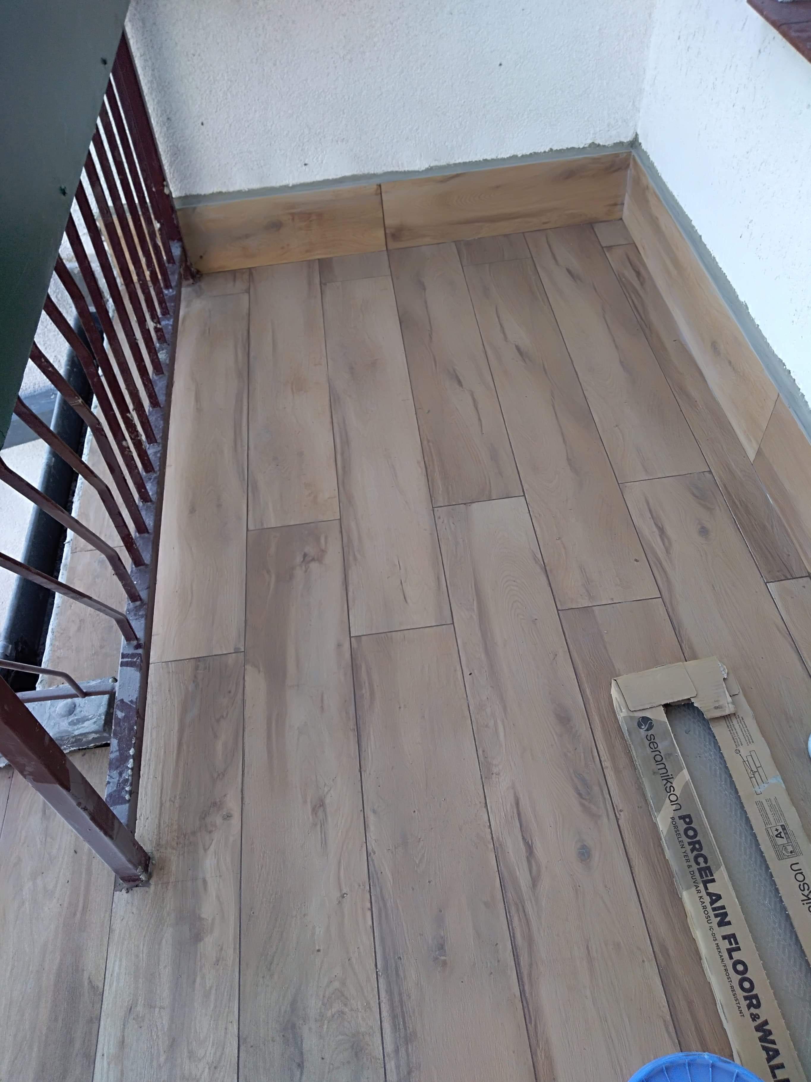 Ułożona podłoga z paneli imitujących drewno na balkonie, widoczna kartonowa paczka paneli Seramiksan Porcelain Floor & Wall.