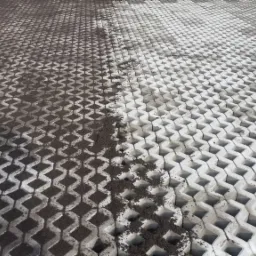 Betonowa ażurowa nawierzchnia częściowo wypełniona ziemią, ukazująca etap prac ziemnych przed ostatecznym wykończeniem.