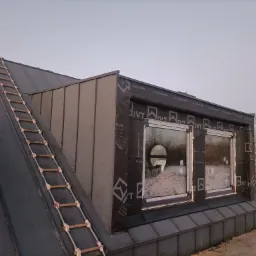 Metalowy dach z oknami dachowymi po obróbce blacharskiej, na dachu drabina sznurowa, widoczne membrany dachowe Aqua Control XL.