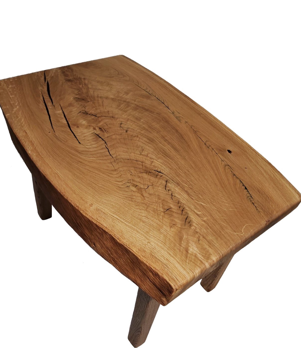 Niski stolik kawowy z blatem z litego drewna dębowego o nieregularnym kształcie krawędzi, eksponujący naturalne pęknięcia i słoje drewna, wsparty na czterech nogach.