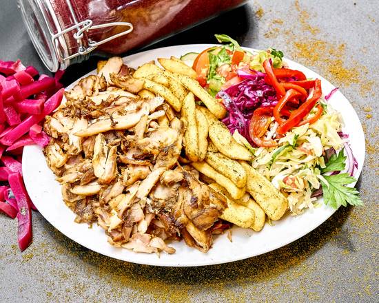 Talerz z porcją grillowanego mięsa, frytek, sałatki coleslaw i warzyw, obok słoik z marynowanymi buraczkami, na szarym tle.