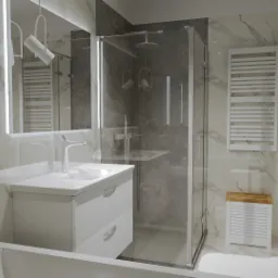 Nowoczesna łazienka z marmurowymi płytkami, białą szafką pod umywalką z chromowaną baterią, szklaną kabiną prysznicową z deszczownicą i grzejnikiem drabinkowym.