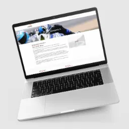 Laptop wyświetla stronę internetową szkoły nauki jazdy z informacjami o kursie prawa jazdy kategorii A, widoczny motocykl w tle.