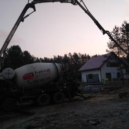 WSK Service - Betoniarka z wysięgnikiem pompuje beton na placu budowy domu jednorodzinnego o zmierzchu.