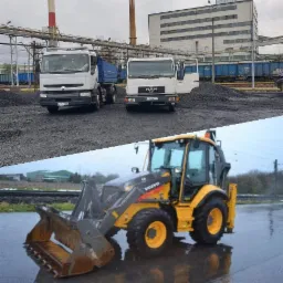 Dwa samochody ciężarowe marki Renault i MAN stojące przed stertą węgla na tle przemysłowym z kominem i budynkiem. Na dole żółta koparko-ładowarka Volvo na mokrym placu.
