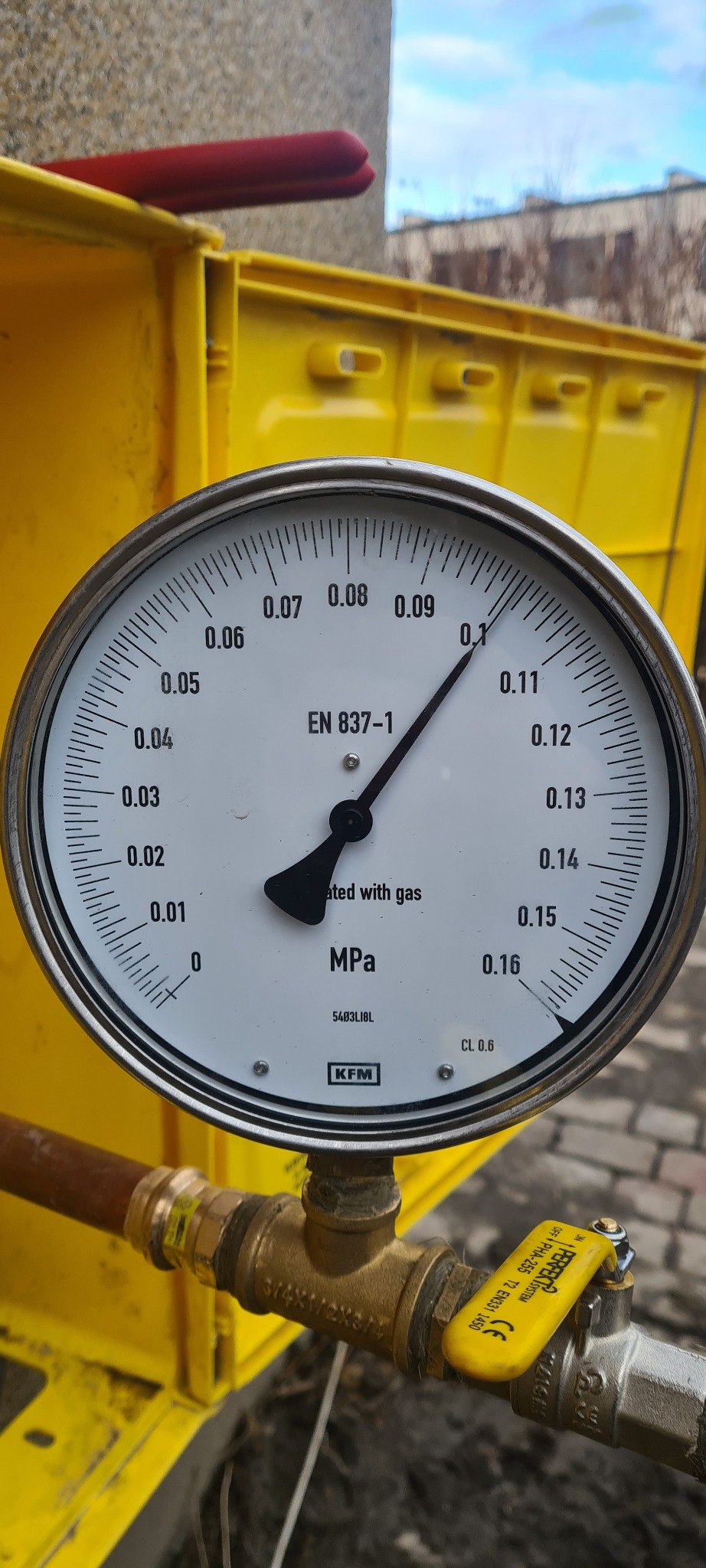 Manometr wskazujący ciśnienie gazu w instalacji, zamontowany na żółtej skrzynce gazowej, widoczny zawór odcinający dopływ gazu.