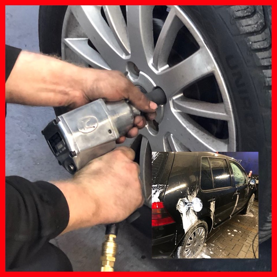 Mechanik odkręca koło samochodu za pomocą klucza pneumatycznego; w tle czarny samochód z pianą na karoserii, prawdopodobnie podczas mycia.