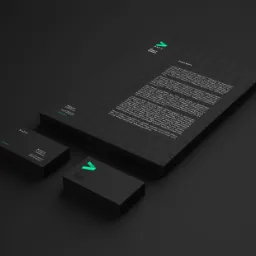 Komplet materiałów firmowych: papier firmowy z tekstem Lorem Ipsum, wizytówki z logo Avra w kolorze czarnym i zielonym, ułożone pod kątem na ciemnym tle.