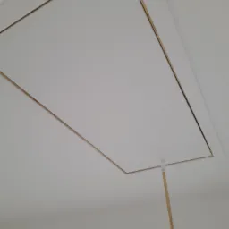 Biały sufit z klapą włazu na poddasze, otwierany za pomocą drewnianego drążka.