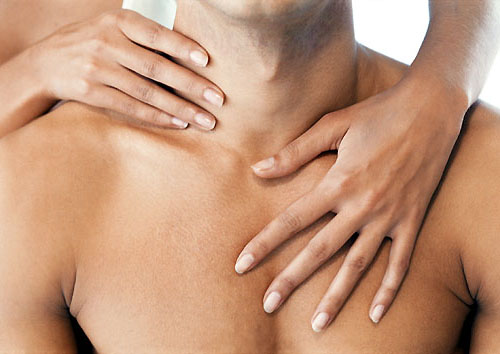 Kobieca dłoń na klatce piersiowej mężczyzny, jasne oświetlenie, gładka skóra.