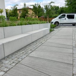 PRODECO BEATA BACH - Nowoczesny ogród z betonową ławką i ścieżką z płyt, obok zaparkowany biały samochód firmy ogrodniczej. Widoczne drzewa i krzewy.