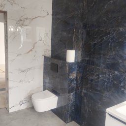 Krzoch-Bud - Wykończona łazienka z marmurowymi płytkami w odcieniach bieli i granatu, wisząca toaleta i zabudowa podtynkowa. Minimalistyczny design z akcentem na naturalne wzory.