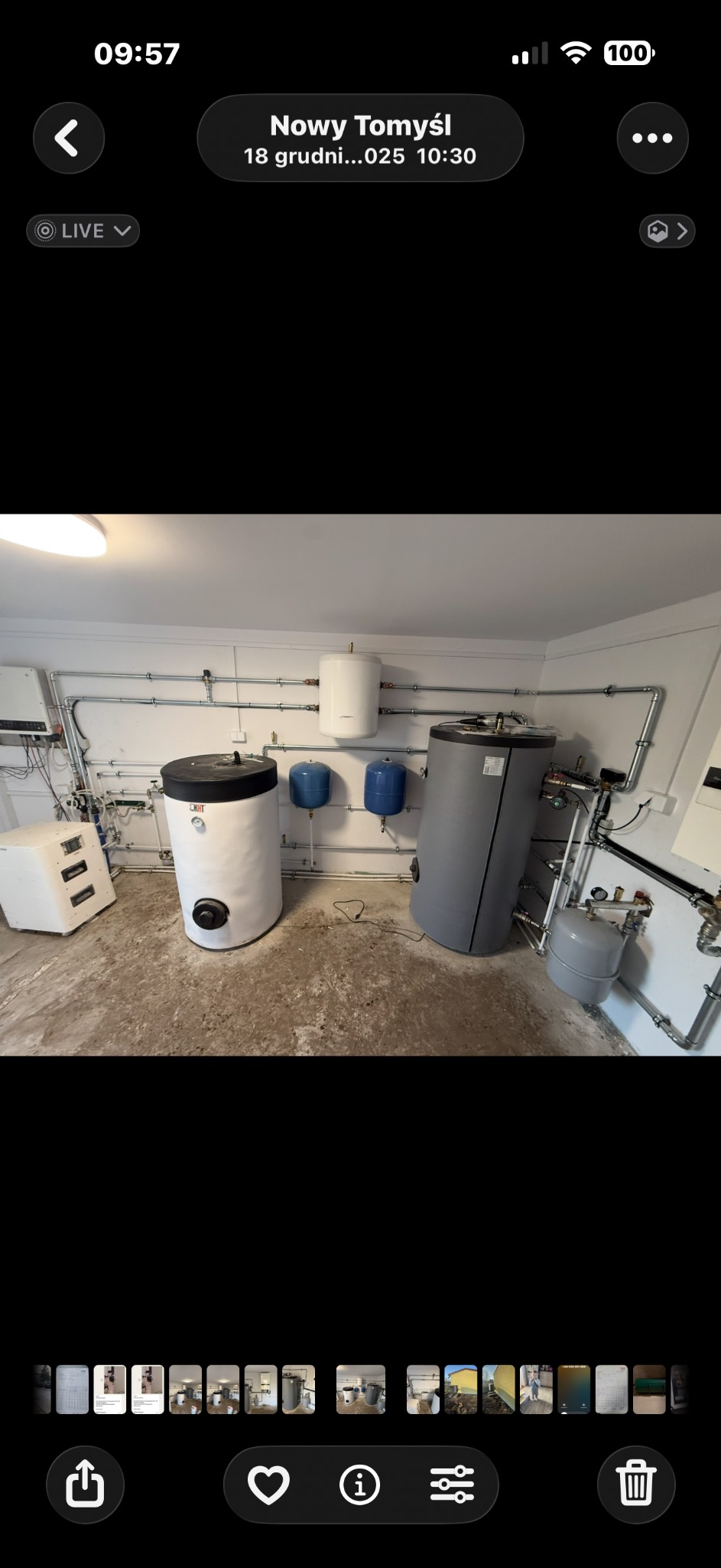 Kompletna instalacja CO w kotłowni: dwa zbiorniki akumulacyjne, bojler, naczynia wzbiorcze i orurowanie. Białe ściany, betonowa posadzka. Widok z perspektywy podłogi.