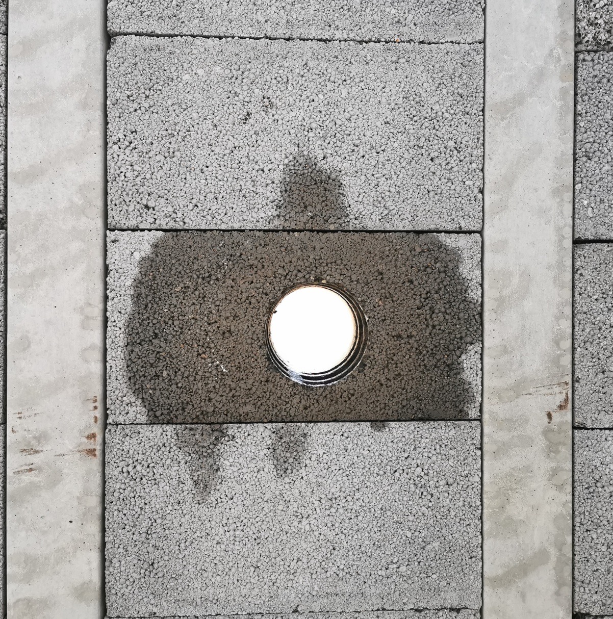 Otwór wentylacyjny w suficie z szarego betonu komórkowego, widoczne ślady wilgoci wokół wylotu.