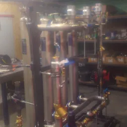 Kompleksowy system uzdatniania wody z rurami, zaworami i zbiornikami ciśnieniowymi, zainstalowany w pomieszczeniu technicznym.