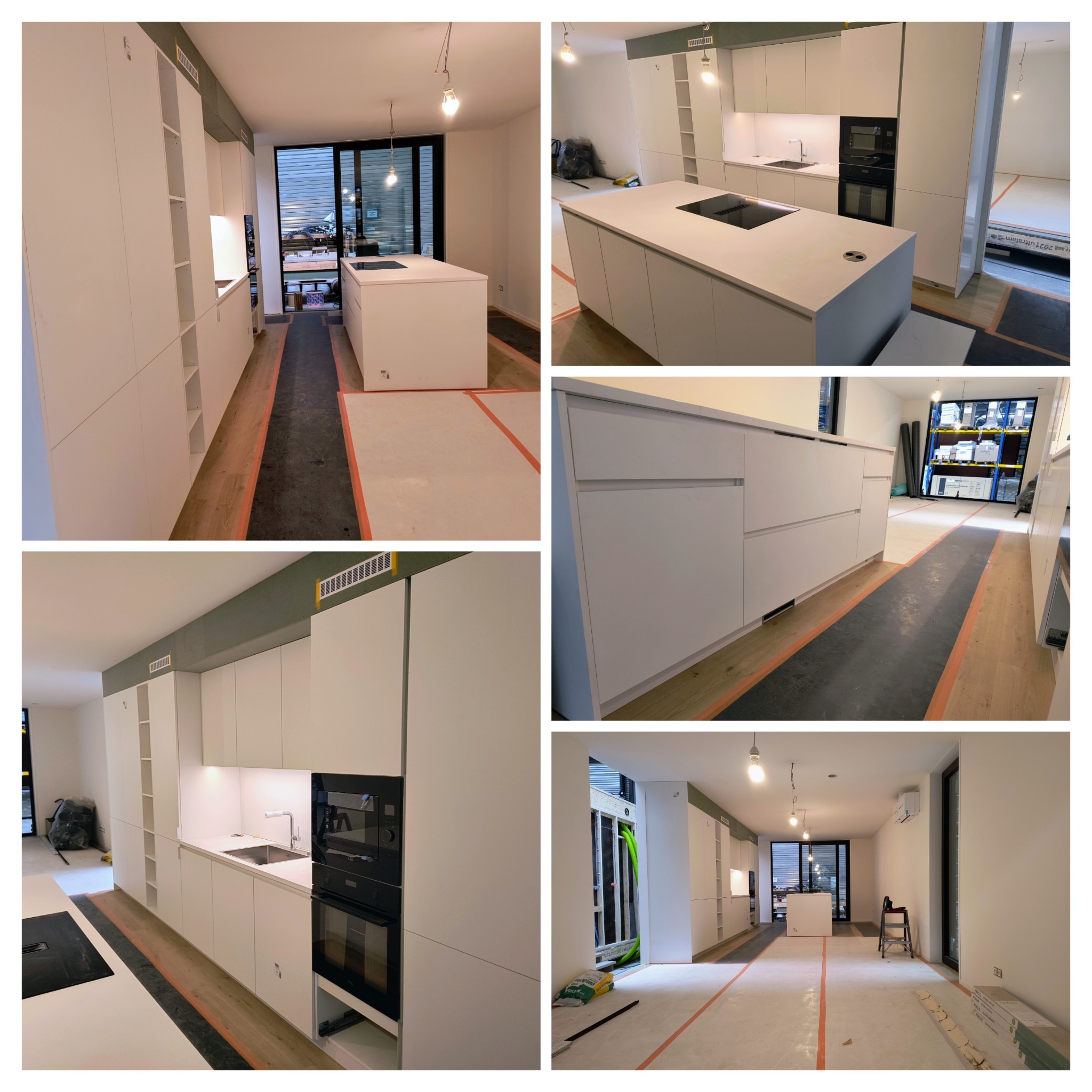 Nowoczesna kuchnia z białymi szafkami i wyspą, widoczne zabezpieczenia podłogi folią malarską, oświetlenie wiszące na kablach, sprzęt AGD w zabudowie.
