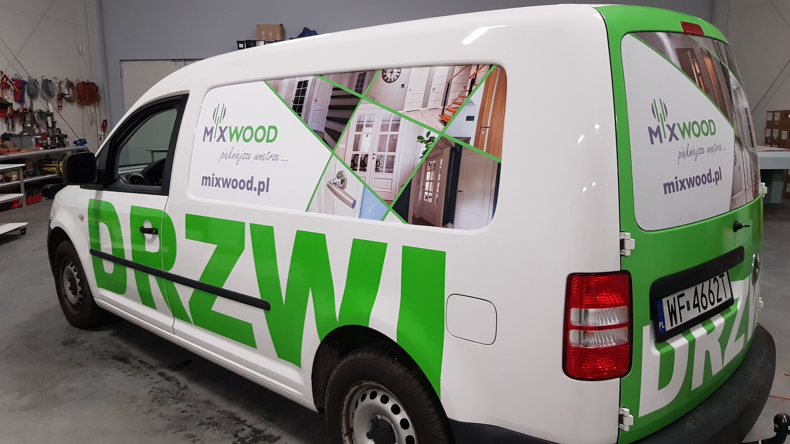 Okolicznościowy samochód dostawczy z grafiką reklamową firmy Mixwood, prezentującą zdjęcia drzwi wkomponowane w geometryczny wzór na boku i tyle pojazdu.