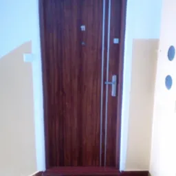 Brązowe drzwi wejściowe z numerem 11 i srebrnymi paskami, widoczne z perspektywy schodów, z wycieraczką 'Welcome Home' u dołu.