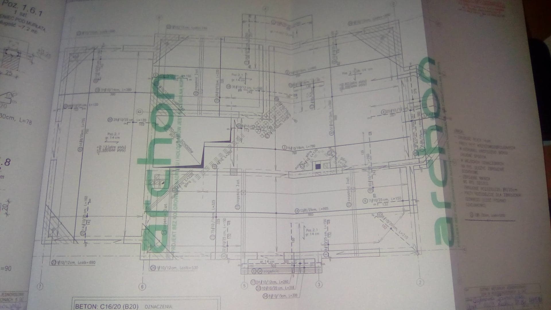 Skan technicznego rysunku architektonicznego z naniesionymi wymiarami i oznaczeniami, częściowo zasłonięty logotypem firmy projektowej.
