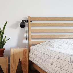 AGNIESZKA LISEK architekt wnętrz - Minimalistyczna sypialnia z drewnianym łóżkiem, geometryczną pościelą, lampką nocną i rośliną doniczkową na drewnianych stolikach nocnych.