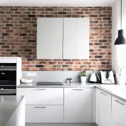 Jasna kuchnia z białymi szafkami i blatem, ceglana ściana w tle, nowoczesne oświetlenie wiszące, sprzęty AGD na blacie, roślina w doniczce.