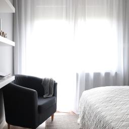 AGNIESZKA LISEK architekt wnętrz - Jasne wnętrze sypialni na poddaszu z białymi zasłonami, szarym fotelem z narzutą, biurkiem z półkami i białym łóżkiem z pikowaną narzutą.