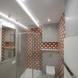 Nowoczesna łazienka z narożną kabiną prysznicową ze srebrnymi profilami, toaletą wiszącą, szarą glazurą i dekoracyjną ścianą w geometryczne wzory w odcieniach czerwieni i bieli.