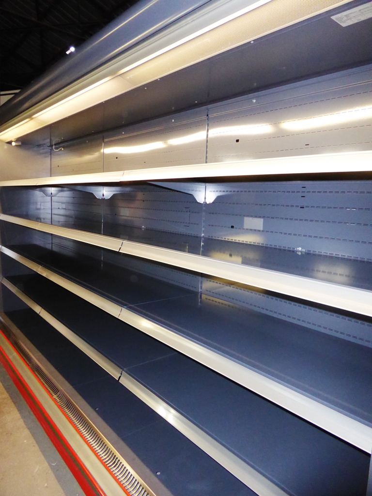 Puste półki w chłodniczej ladzie sklepowej z oświetleniem LED, widoczne otwory wentylacyjne w dolnej części.