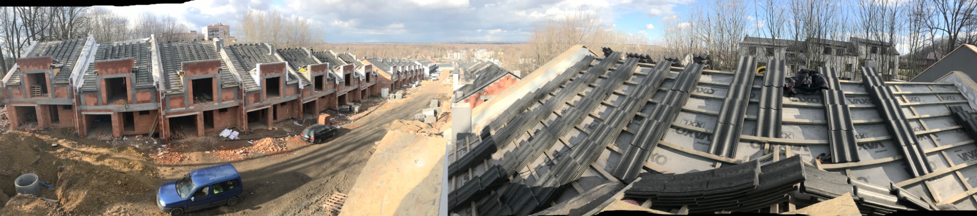Panorama z budowy szeregu domów w stanie surowym otwartym, widoczne przygotowanie dachu z łatami i membraną oraz ułożone dachówki, w tle krajobraz miejski.