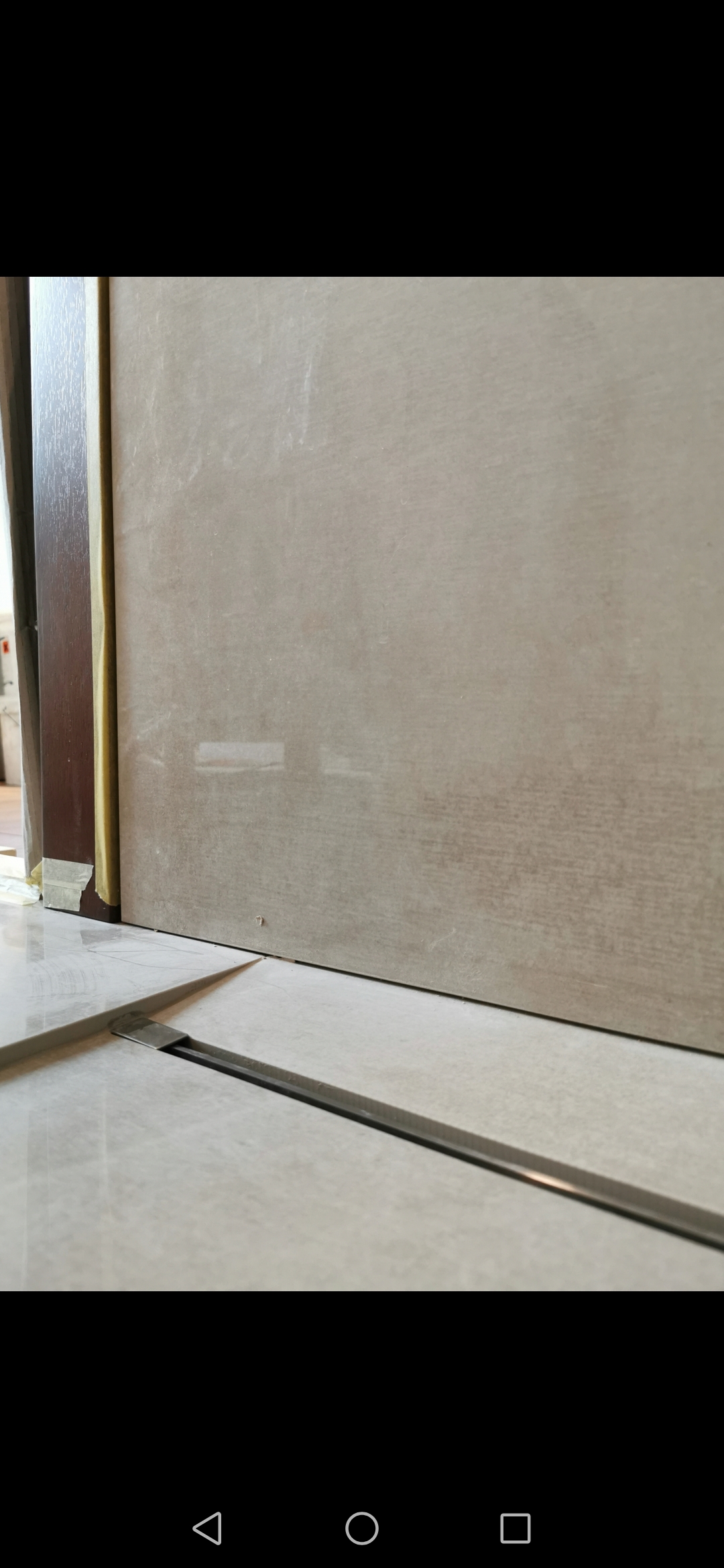 Beżowe płytki ścienne i podłogowe, przycięte listwą progową, widoczne przy drzwiach w Wolsztynie, z bliska.