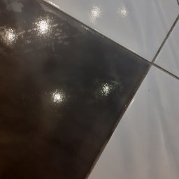 JUŻ w PORZĄDKU - Błyszczące, czarno-białe płytki podłogowe po sprzątaniu w układzie szachownicy, widoczne fugi w Sucha Beskidzka. Czystość i połysk.