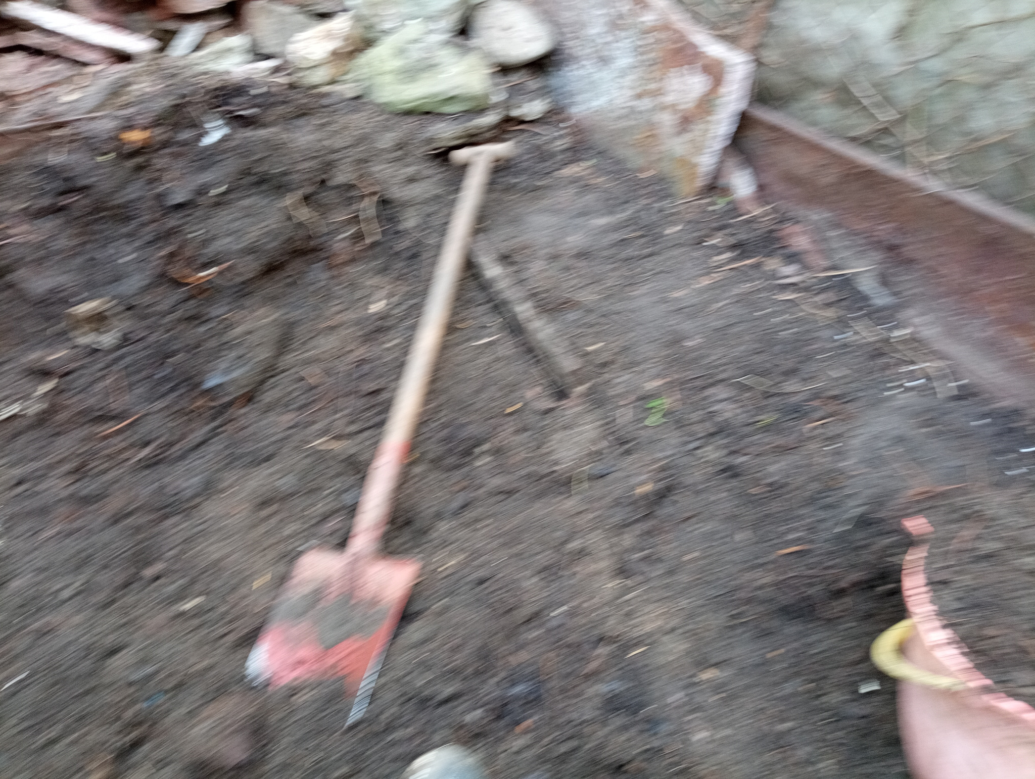 Ziemia z łopatą i kamieniami. Przygotowanie terenu pod sadzenie roślin. Nierówna powierzchnia ziemi.