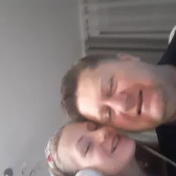 Portret selfie ojca i córki, obrócony o 90 stopni, uśmiechnięci, z bliska, widoczne fragmenty twarzy i tła.