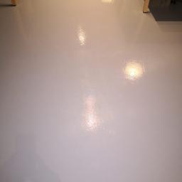 SPIC AND SPAN. Home & Office Cleaning - Błyszcząca, jasnoszara podłoga po umyciu, z widocznymi refleksami światła i fragmentami nóg biurek.