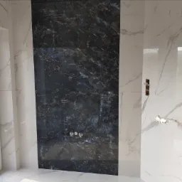 Ściana łazienki wyłożona białymi i czarnymi płytkami imitującymi marmur, z widocznymi przyłączami do armatury i oknem z widokiem na zewnątrz.