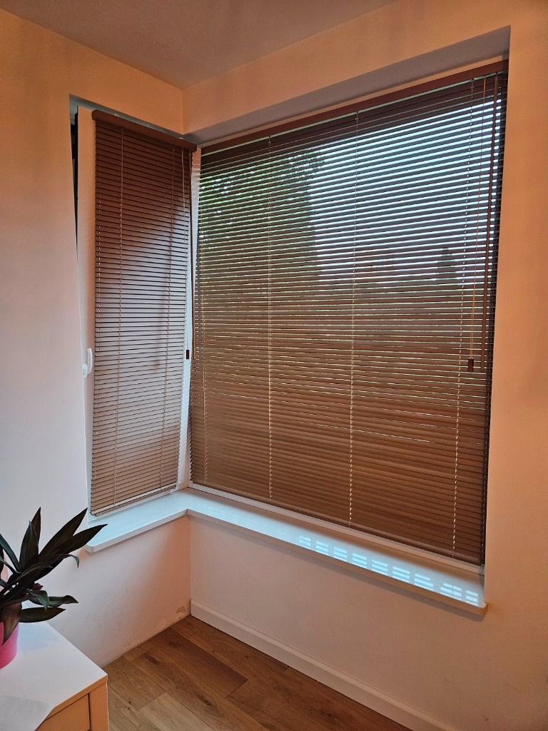 Żaluzje drewniane 25 mm montowane na ramie okiennej.