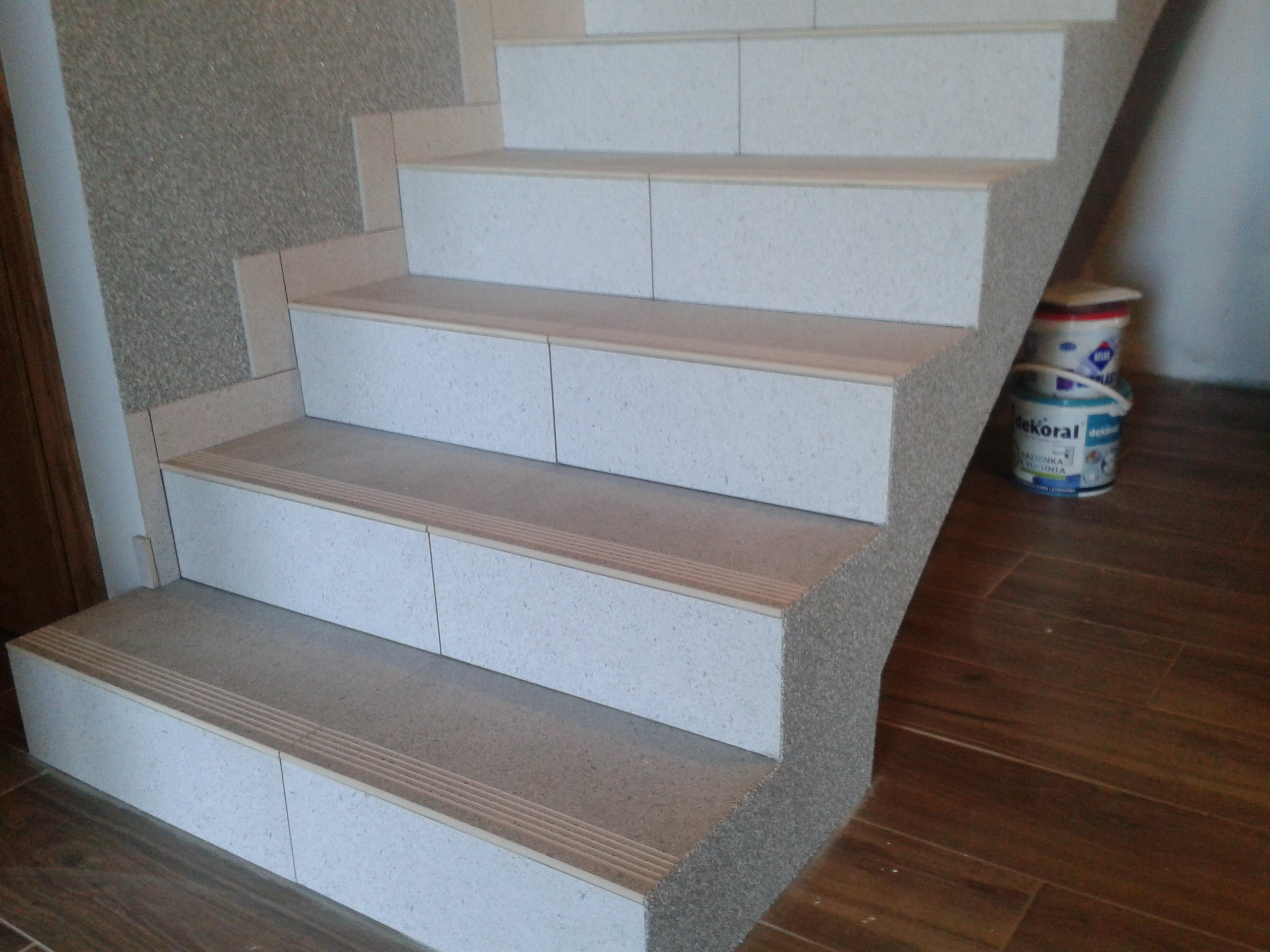 Wykończone płytkami schody wewnętrzne w Nowej Wsi Lęborskiej, z widocznymi profilami antypoślizgowymi na krawędziach stopni i wiaderkami z farbą w tle.