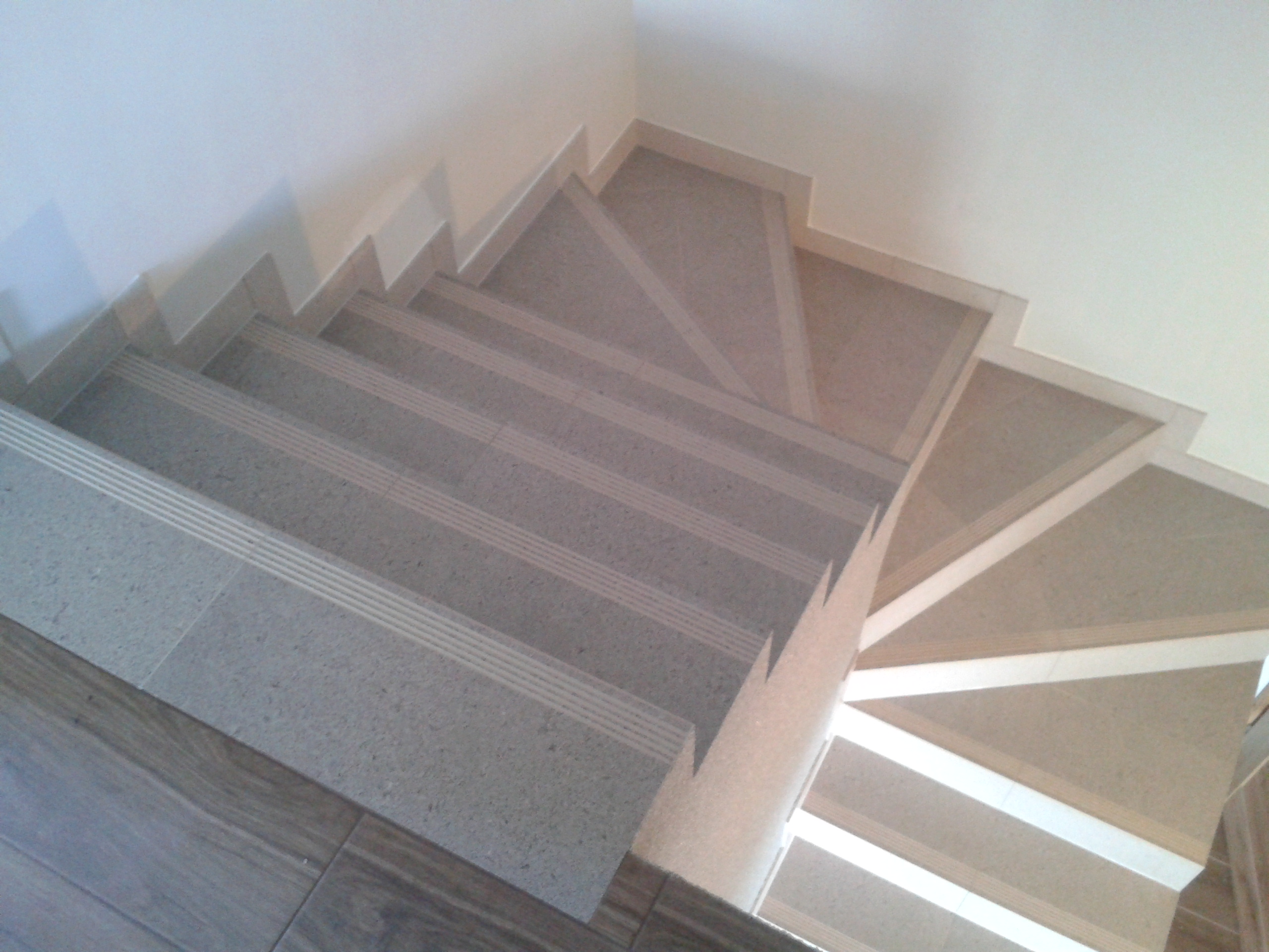 Wykończone schody wewnętrzne z szarymi płytkami i antypoślizgowymi paskami w Nowej Wsi Lęborskiej, widok z góry.