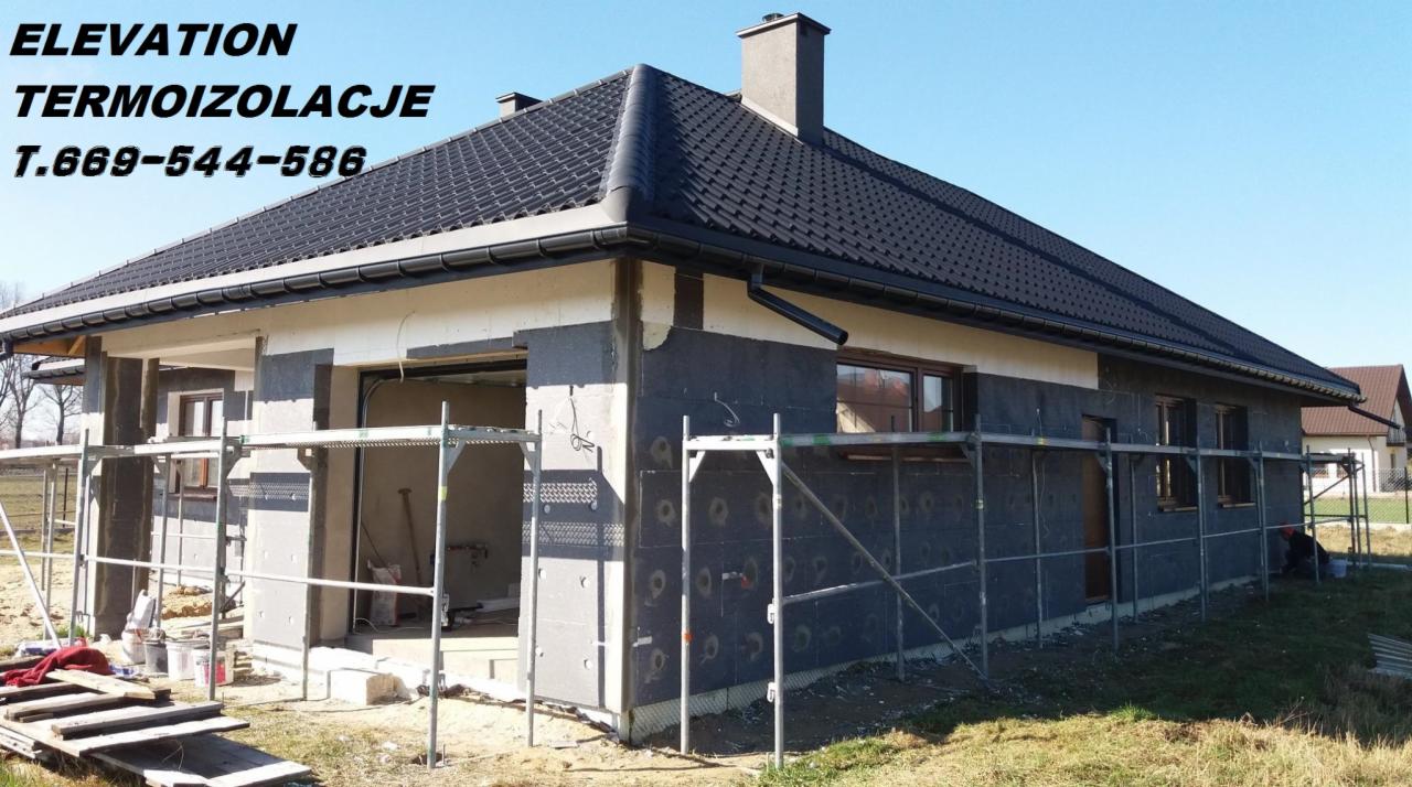 Dom jednorodzinny w trakcie prac związanych z ociepleniem elewacji, widoczne rusztowania, płyty izolacyjne grafitowe i białe, przygotowane do dalszych etapów prac.