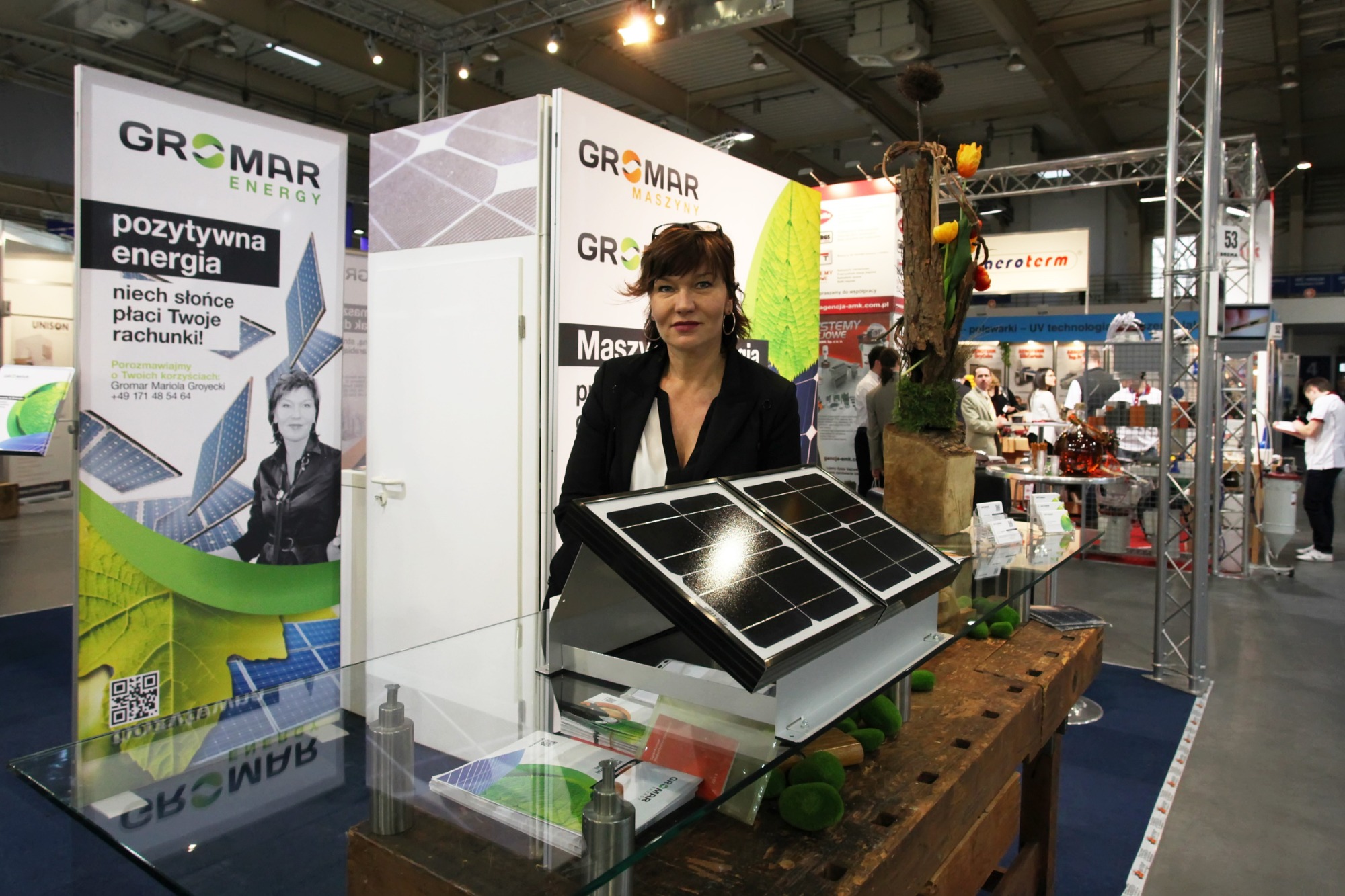 Stoisko targowe firmy Gromar Energy z panelem słonecznym na stole, prezentacja oferty z wykorzystaniem materiałów reklamowych i ekspozycji modelowych.